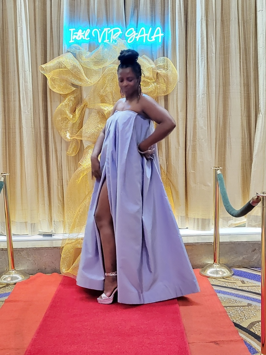 Event planner Josiane Djachechi standing before the completed gold gala backdrop at The Mayflower Hotel in Washington, D.C.