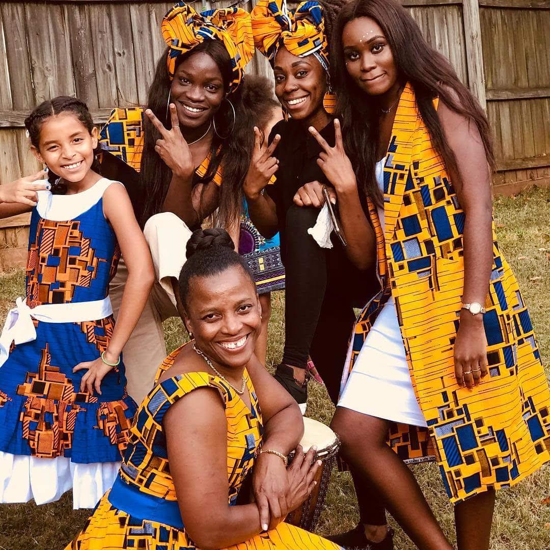 Family group in matching gold and blue print traditional attire with a drum